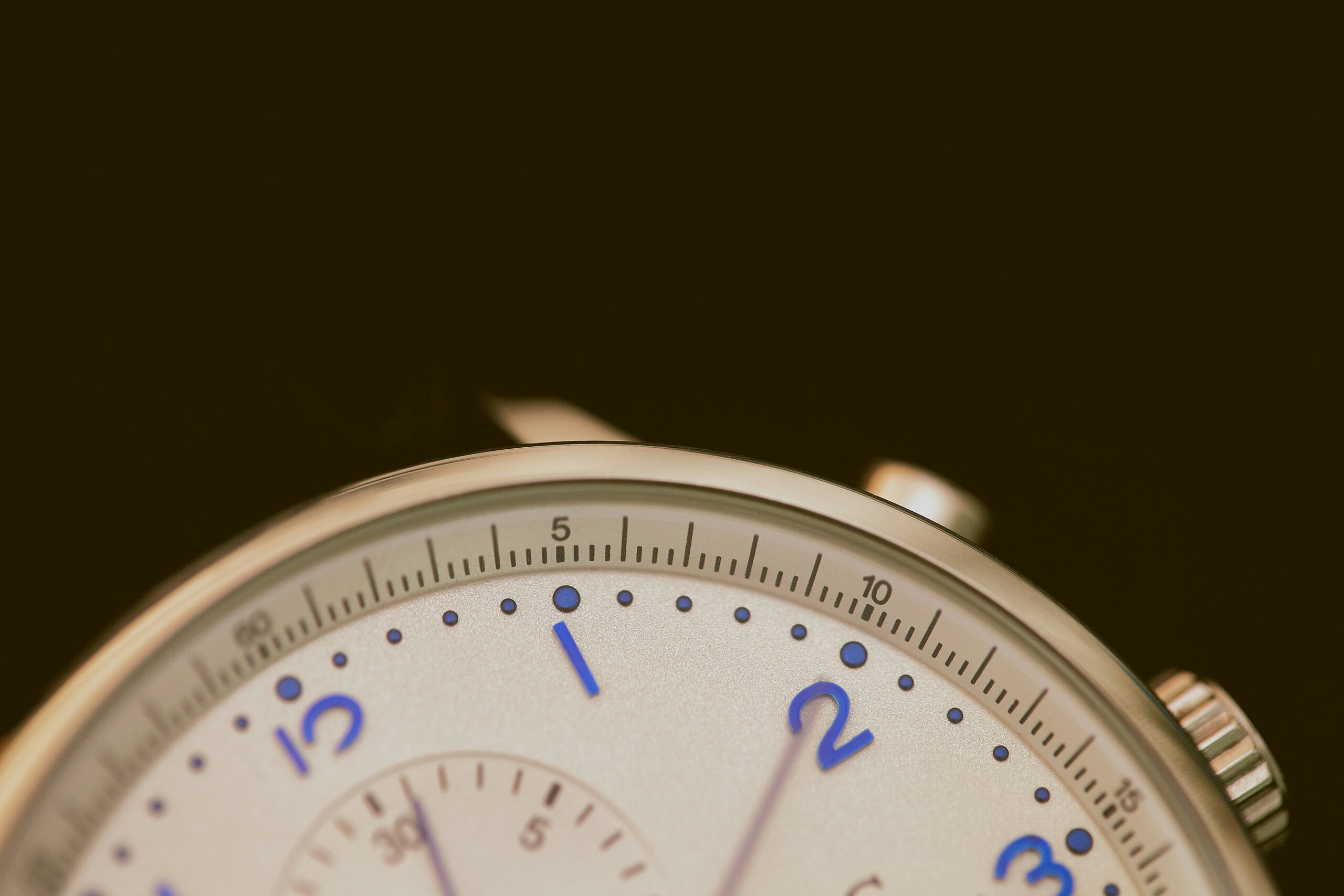 a watch with a gold rim and blue numbers on a black background