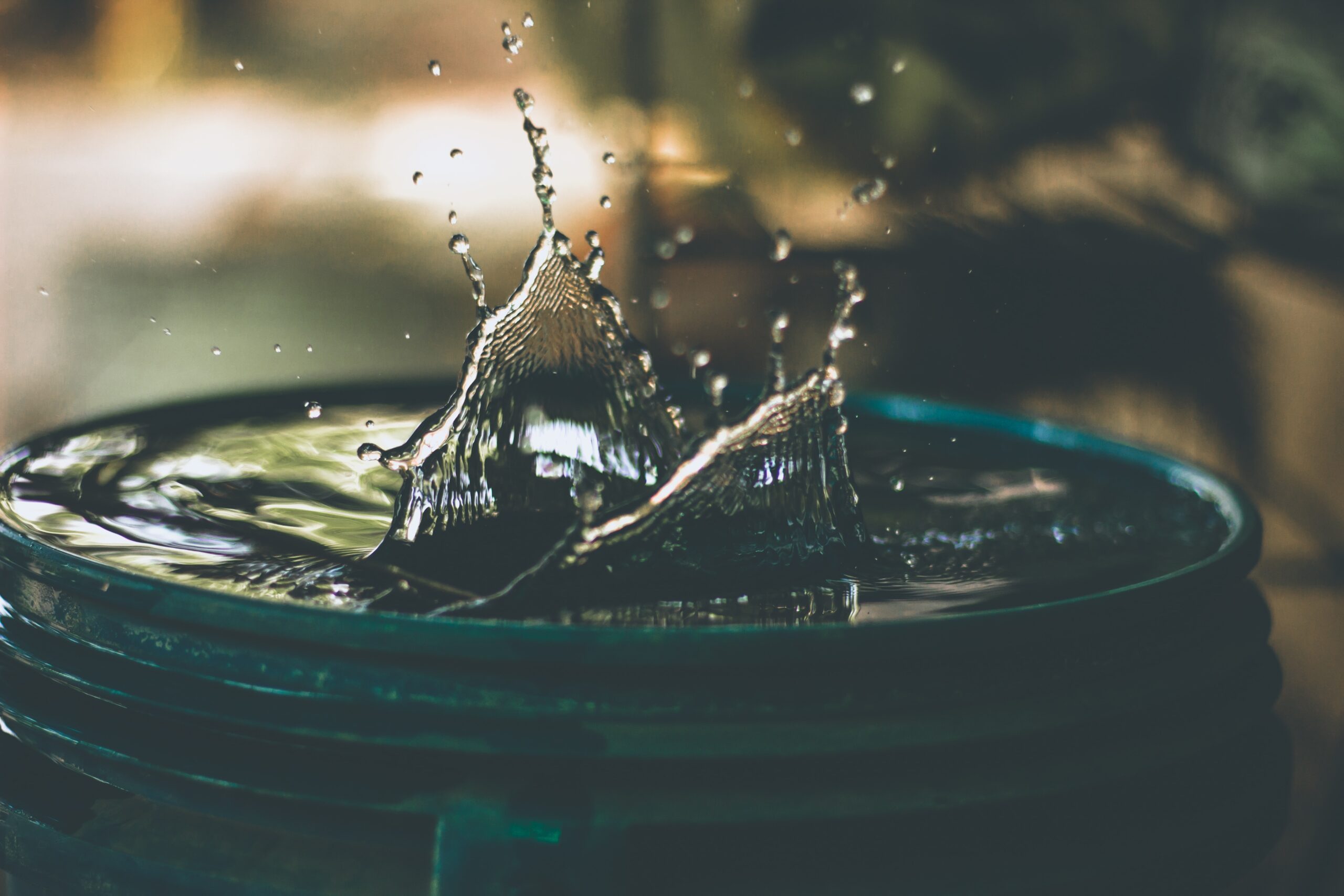 water bouncing up in a barrel in the background green grass and sunlight