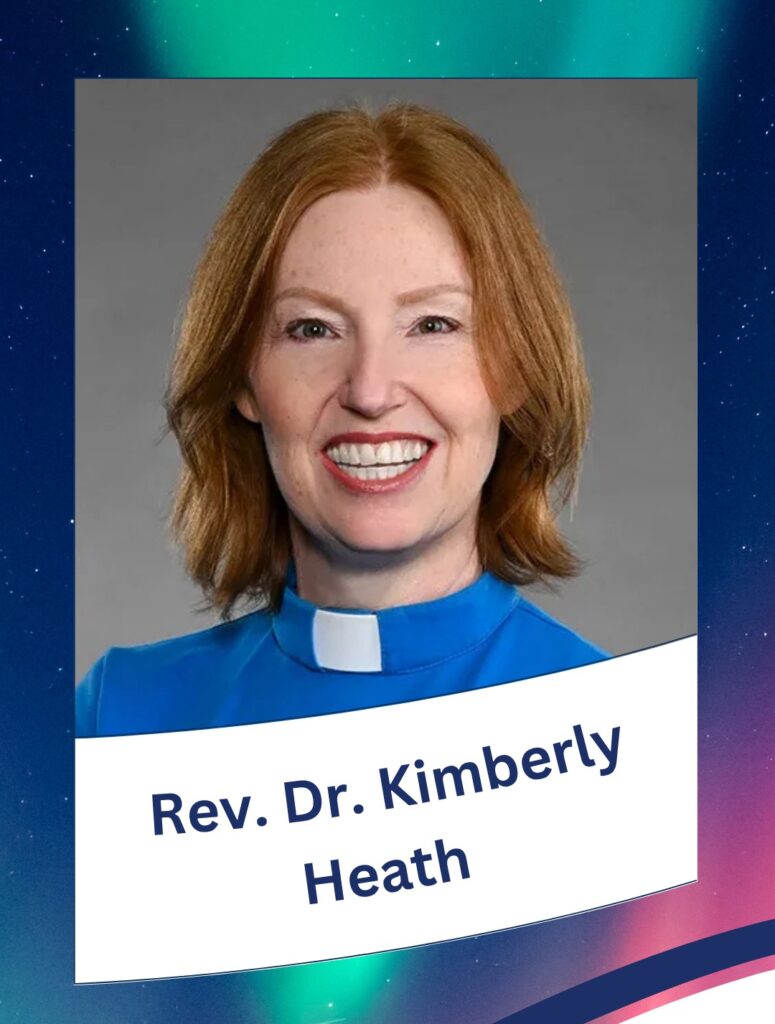 a woman with shoulder length red hair, smiling, wearing a blue shirt with a white clergy collar